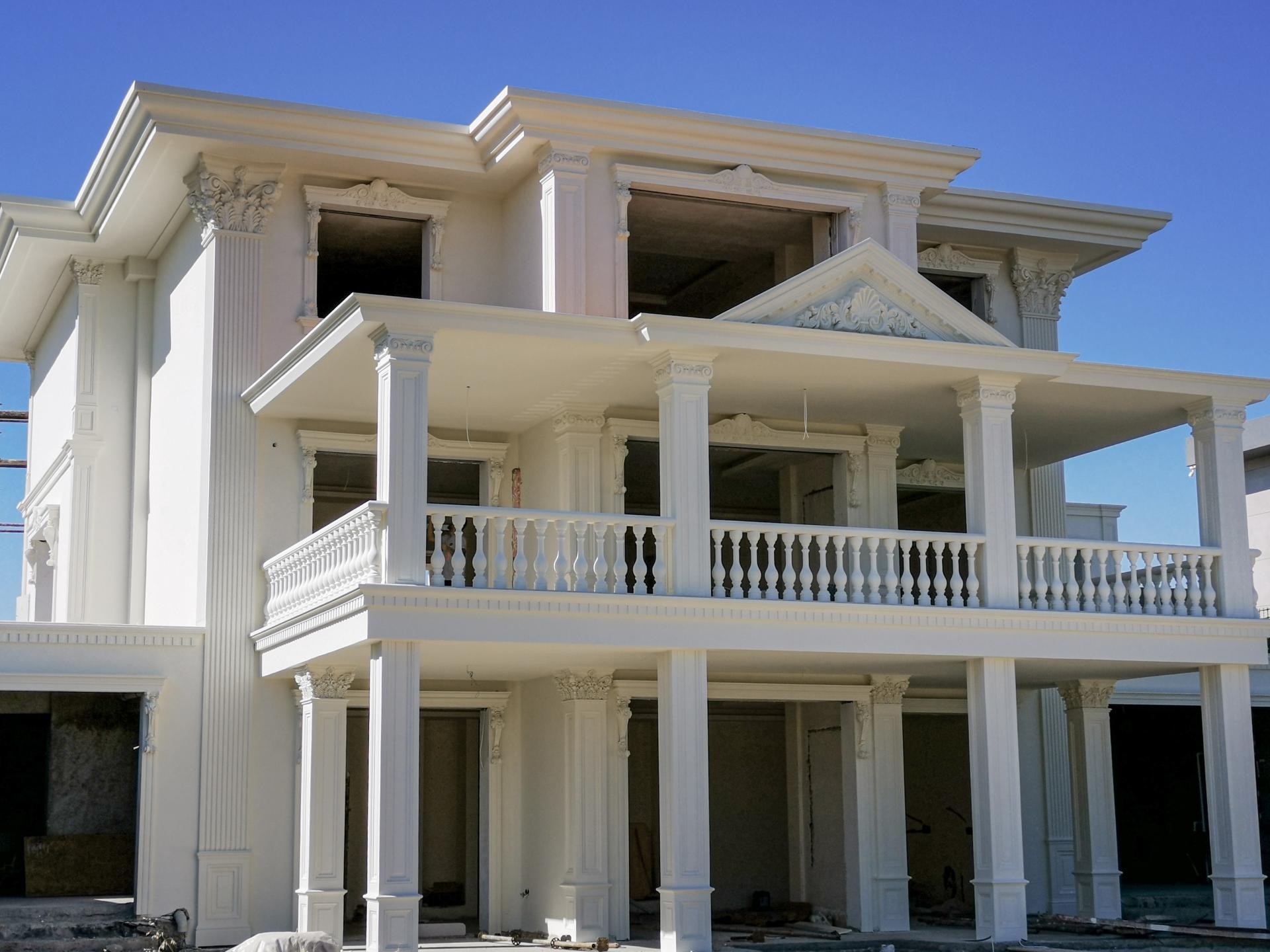 Klasik tarzda beyaz poliüretan pilaster sütunlar, dekoratif pencere söveleri ve balkon korkulukları ile süslenmiş villa dış cephesi.