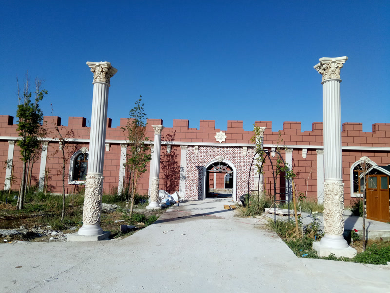 Kızıl tuğla duvarlı iş yeri girişinde poliüretan sütunlar, yuvarlak kemerli kapı ve desenli dış cephe panelleri.