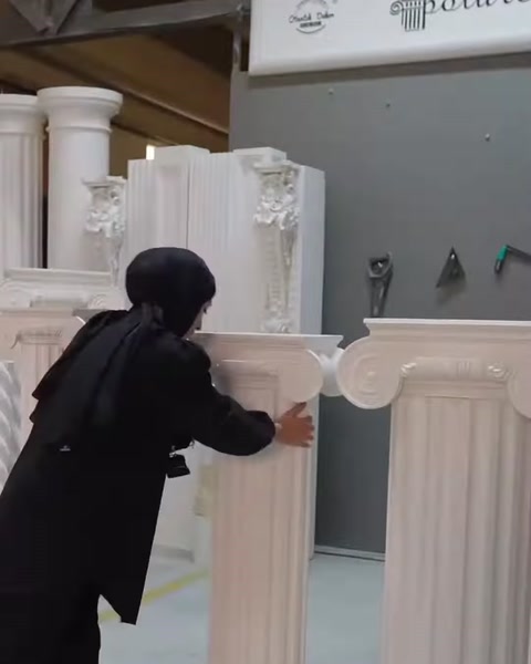 Sunucu geniş gövdeli sütun sehpa modelini iki eliyle inceliyor