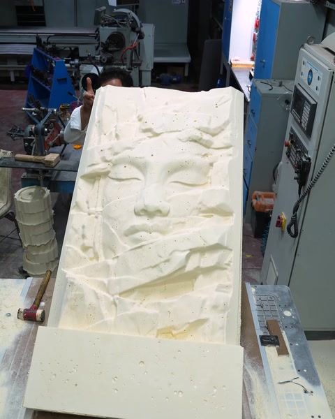 Yüz rölyefi işlenmiş panel başka makinenin yanında görünüyor