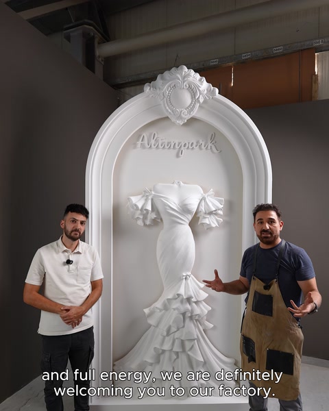 İki ekip üyesi tamamlanmış rölyef önünde kamera karşısında duruyor.