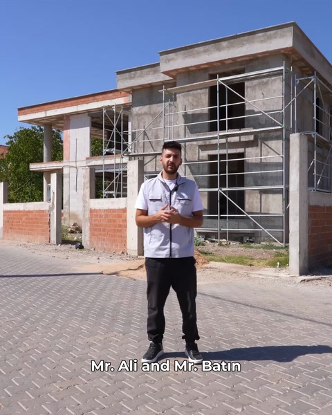 Ekip üyesi inşaat halindeki villa önünde tanıtım yapıyor