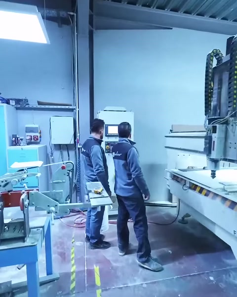 İki çalışan CNC panel işleme sürecini makine başında takip ediyor